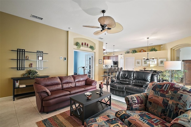 tiled living room featuring ceiling fan with notable chandelier