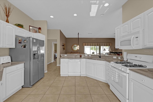 kitchen with white appliances, white cabinets, sink, hanging light fixtures, and kitchen peninsula