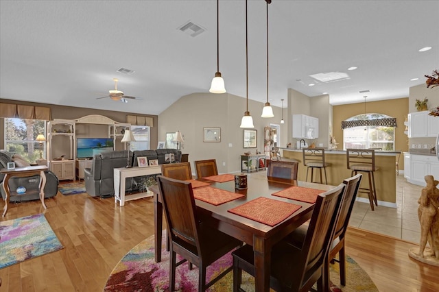 dining area featuring ceiling fan, light hardwood / wood-style flooring, and vaulted ceiling