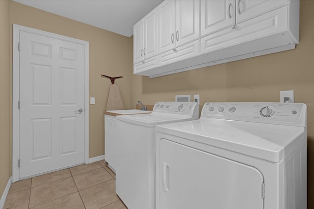 clothes washing area featuring washing machine and clothes dryer, sink, light tile patterned flooring, and cabinets