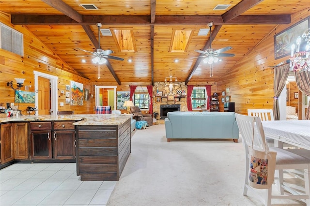 interior space featuring vaulted ceiling with beams, light stone countertops, a fireplace, and wooden walls