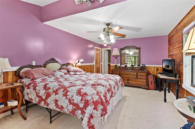 bedroom featuring ceiling fan, wood walls, and light carpet