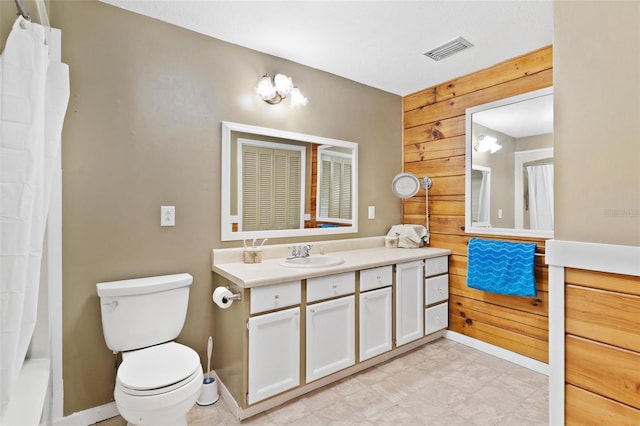 bathroom with vanity, wood walls, and toilet