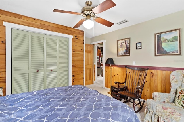 bedroom featuring carpet, wood walls, a closet, and ceiling fan