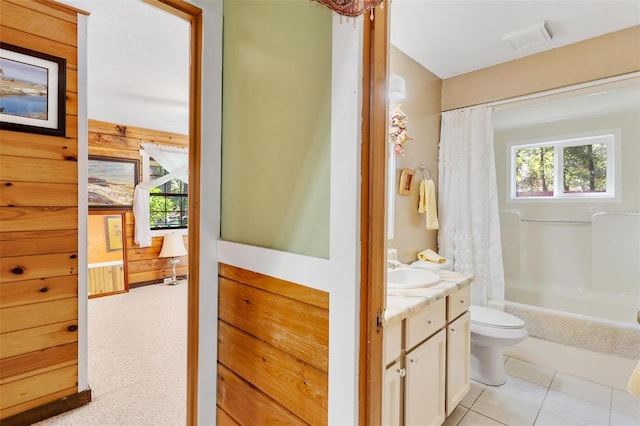 full bathroom with vanity, wooden walls, tile patterned flooring, toilet, and shower / tub combo with curtain