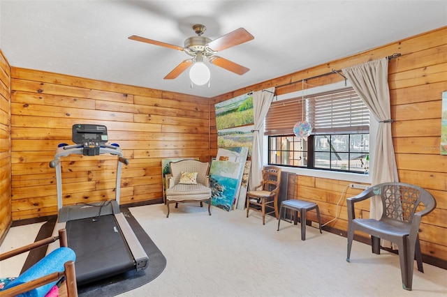 exercise area with wooden walls, carpet floors, and ceiling fan