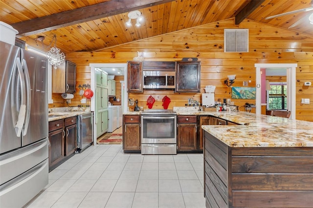 kitchen featuring appliances with stainless steel finishes, light tile patterned floors, pendant lighting, and wood walls