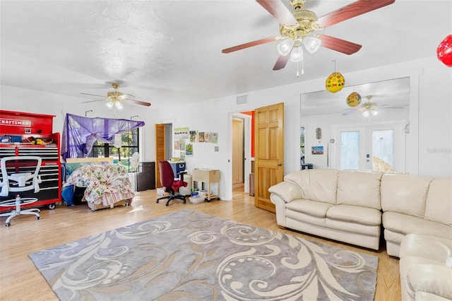 living room with light hardwood / wood-style floors, a wealth of natural light, and french doors