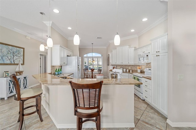 kitchen featuring tasteful backsplash, light stone countertops, white appliances, a peninsula, and a kitchen bar