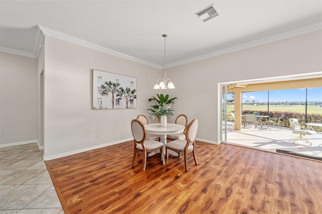 dining space with baseboards, visible vents, a notable chandelier, and ornamental molding