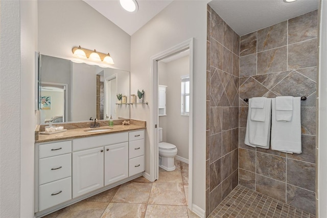 full bath featuring baseboards, tiled shower, toilet, vaulted ceiling, and vanity