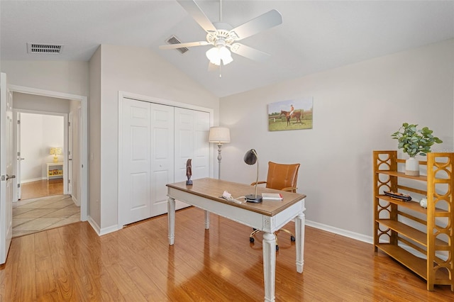 home office featuring baseboards, visible vents, a ceiling fan, light wood-style flooring, and vaulted ceiling