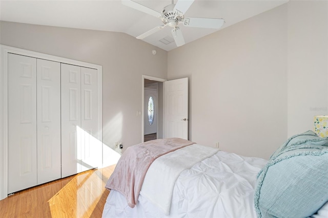 bedroom with light wood-type flooring, a closet, vaulted ceiling, and ceiling fan