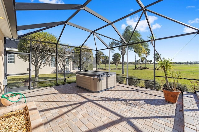 view of patio / terrace featuring glass enclosure and a hot tub