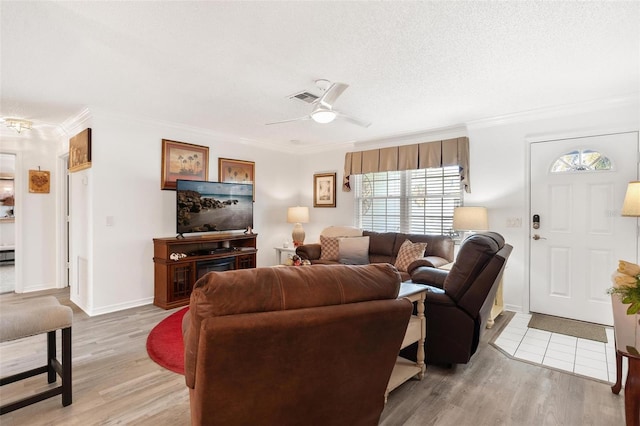 living room with ceiling fan, ornamental molding, a textured ceiling, and light hardwood / wood-style flooring