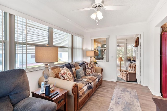 living room with a textured ceiling, light wood-type flooring, ceiling fan, and a healthy amount of sunlight