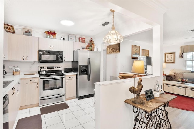 kitchen with black appliances, pendant lighting, light countertops, and ornamental molding