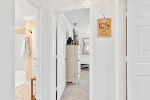 hall featuring light tile patterned floors, visible vents, ornamental molding, a textured ceiling, and light carpet
