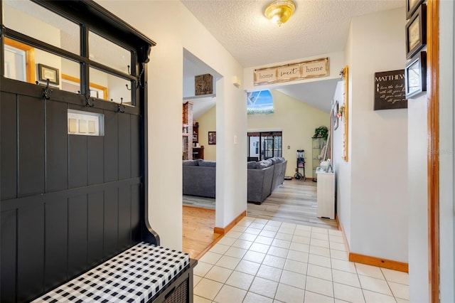 interior space featuring light tile patterned flooring, lofted ceiling, and a textured ceiling