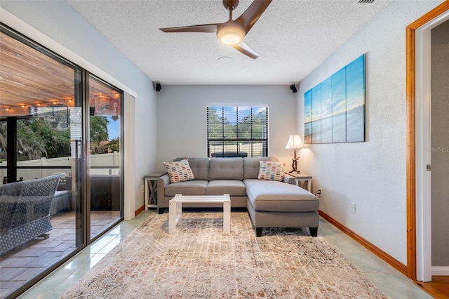 living room featuring ceiling fan, a textured ceiling, tile patterned floors, and a healthy amount of sunlight