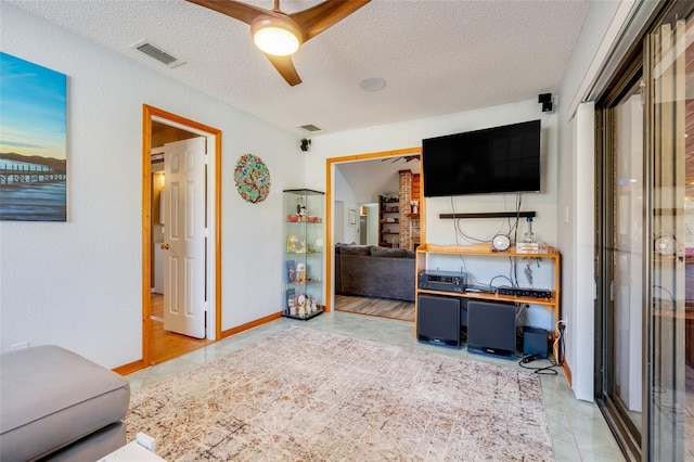 living room featuring ceiling fan, tile patterned flooring, and a textured ceiling