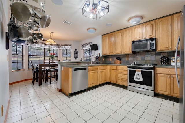 kitchen with light tile patterned floors, hanging light fixtures, backsplash, stainless steel appliances, and kitchen peninsula