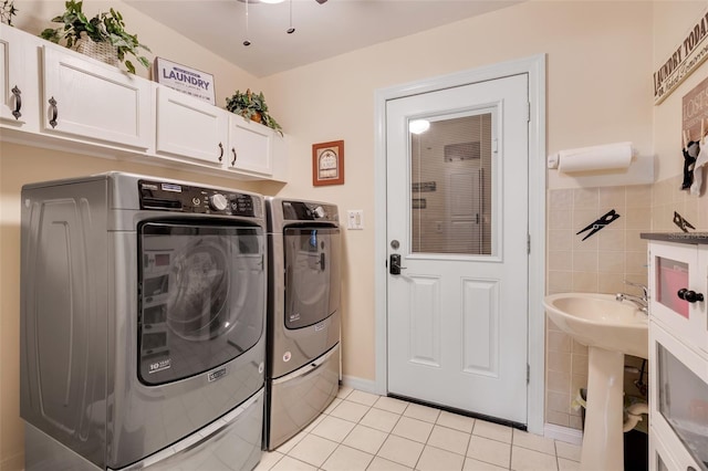 laundry area featuring tile walls, cabinets, light tile patterned floors, and washer and dryer