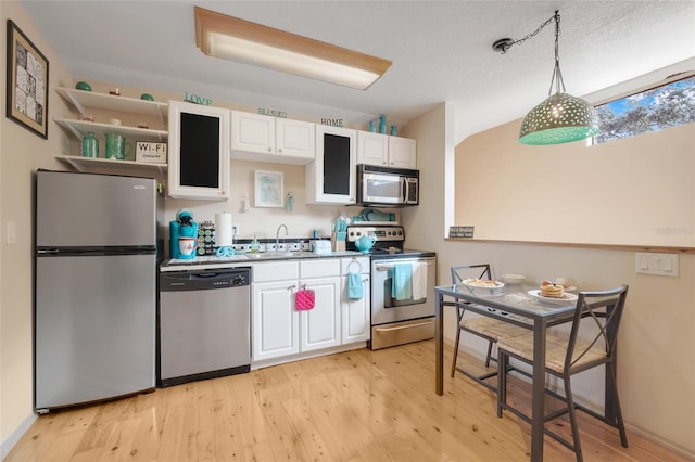 kitchen featuring sink, stainless steel appliances, light hardwood / wood-style floors, white cabinets, and decorative light fixtures