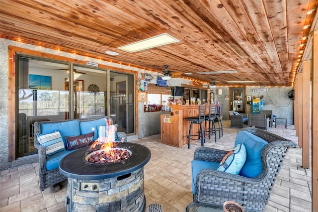 view of patio / terrace with exterior bar, an outdoor living space with a fire pit, and ceiling fan