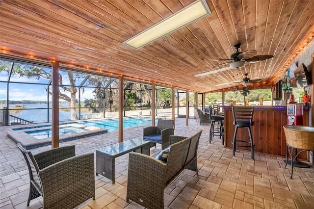 view of patio / terrace with a water view, exterior bar, a pool with hot tub, and glass enclosure