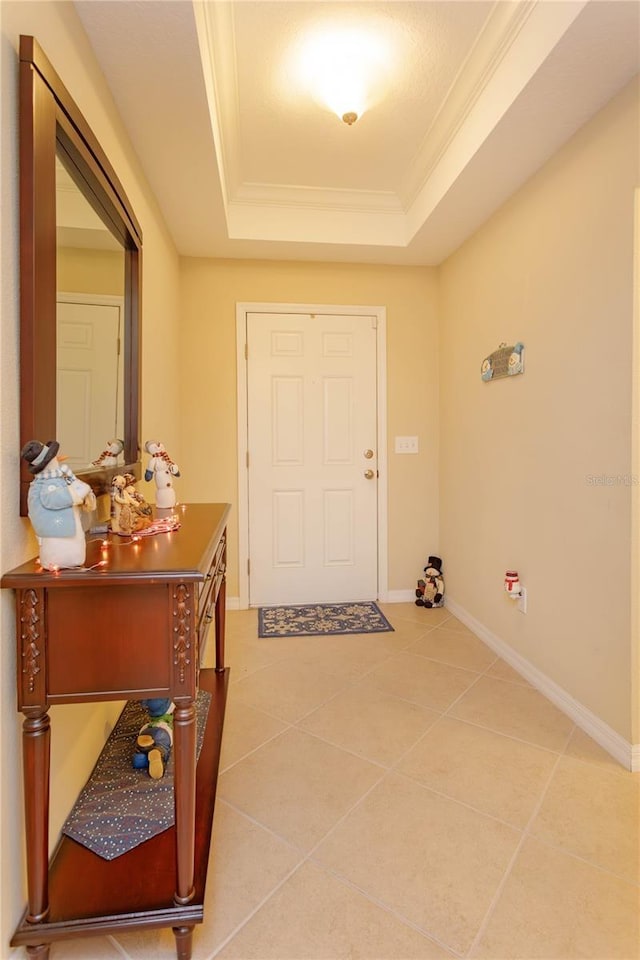 tiled foyer entrance featuring a raised ceiling and ornamental molding