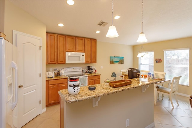 kitchen with a kitchen bar, a wealth of natural light, pendant lighting, and white appliances