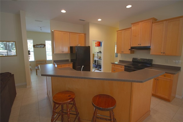 kitchen featuring a breakfast bar, light brown cabinets, light tile patterned floors, and black appliances