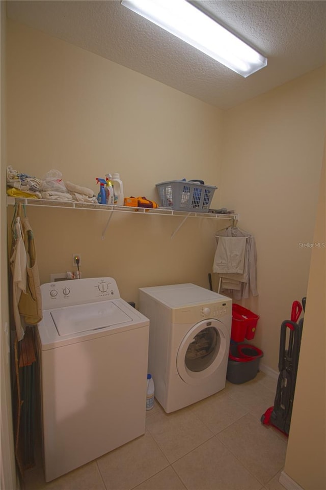 laundry room with washer and clothes dryer, light tile patterned floors, and a textured ceiling