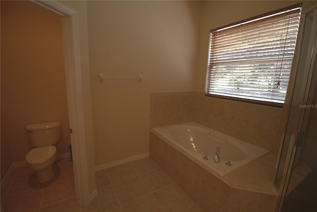 bathroom with tile patterned floors, a relaxing tiled tub, and toilet