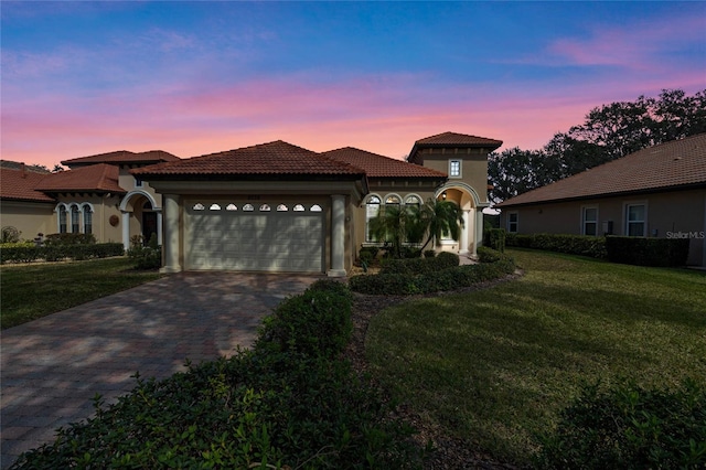 mediterranean / spanish-style house featuring a garage and a lawn