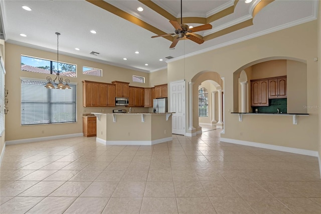 kitchen featuring crown molding, appliances with stainless steel finishes, a kitchen island, pendant lighting, and ceiling fan with notable chandelier