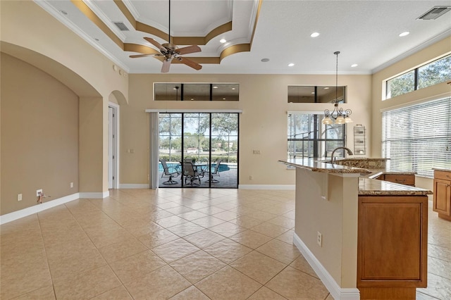 kitchen with sink, hanging light fixtures, ornamental molding, a kitchen breakfast bar, and stone counters