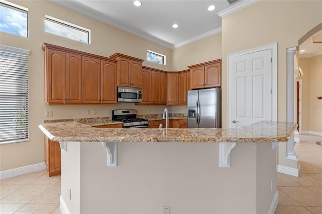 kitchen with light tile patterned floors, stainless steel appliances, a breakfast bar, and a center island with sink