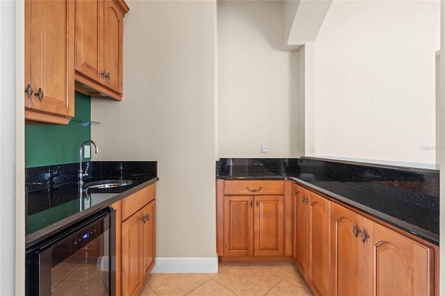 kitchen featuring sink, light tile patterned floors, beverage cooler, and dark stone counters