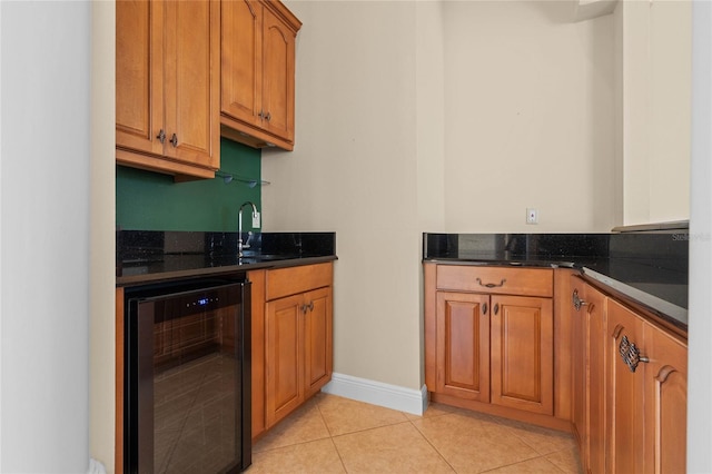 kitchen featuring dark stone counters, beverage cooler, sink, and light tile patterned floors