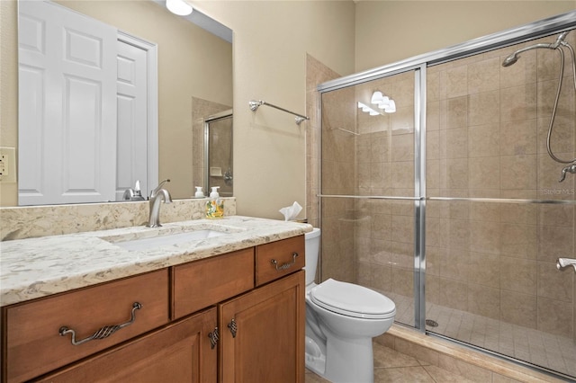 bathroom featuring vanity, toilet, tile patterned floors, and a shower with shower door