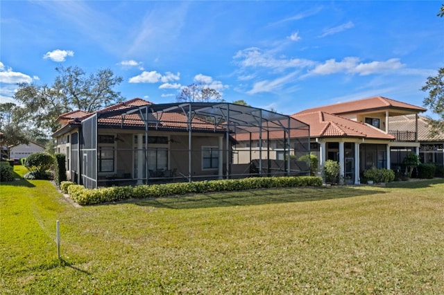 rear view of house with glass enclosure and a lawn