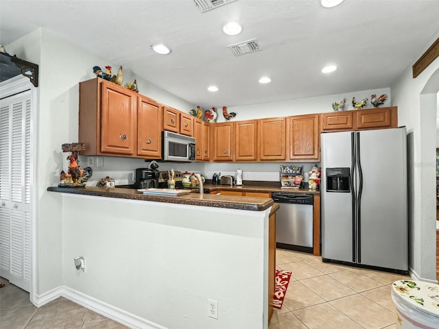 kitchen featuring kitchen peninsula, appliances with stainless steel finishes, light tile patterned floors, and sink