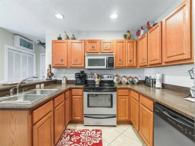 kitchen with light tile patterned flooring, stainless steel appliances, kitchen peninsula, and sink