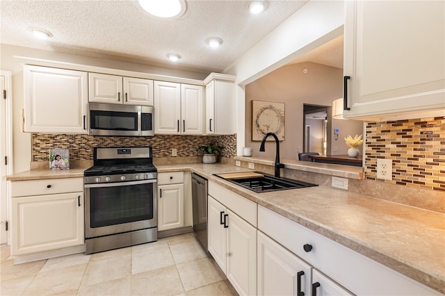 kitchen featuring decorative backsplash, sink, white cabinets, and appliances with stainless steel finishes