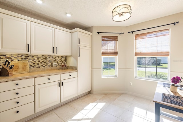 kitchen with white cabinetry, decorative backsplash, light tile patterned floors, and a textured ceiling