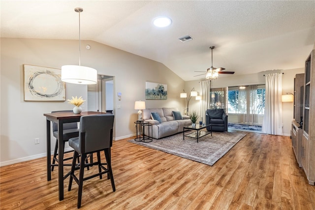 living room featuring light hardwood / wood-style flooring, vaulted ceiling, and ceiling fan