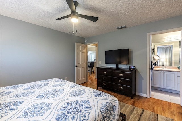 bedroom featuring connected bathroom, ceiling fan, sink, hardwood / wood-style floors, and a textured ceiling