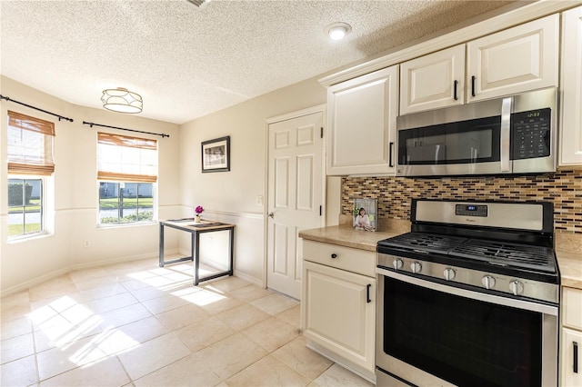 kitchen with appliances with stainless steel finishes, light tile patterned floors, a textured ceiling, and backsplash